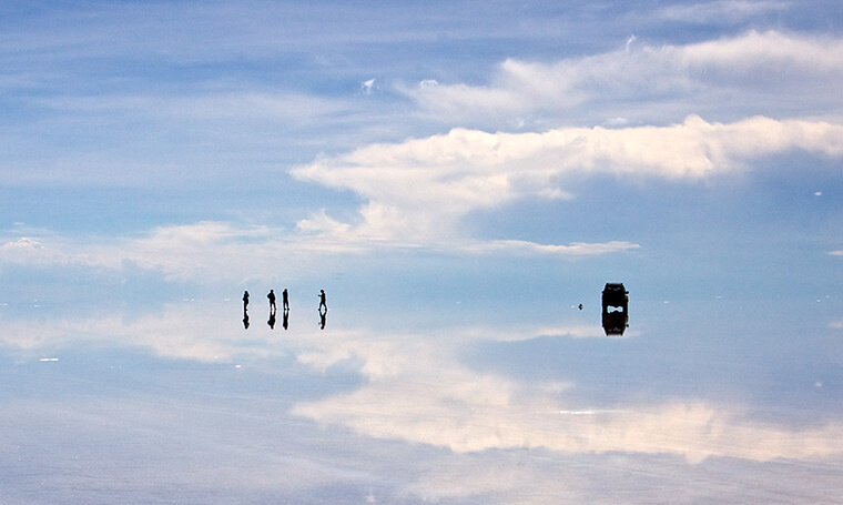 personas y vehículos sobre efecto espejo en Salar de Uyuni