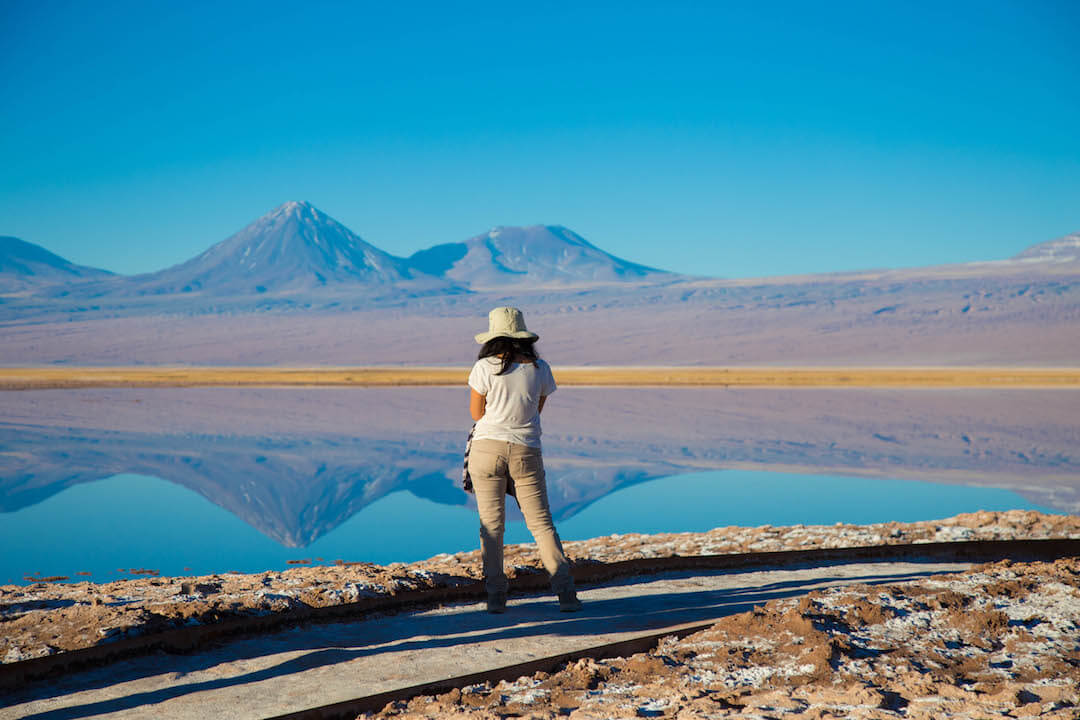 Turista frente a laguna y volcán.