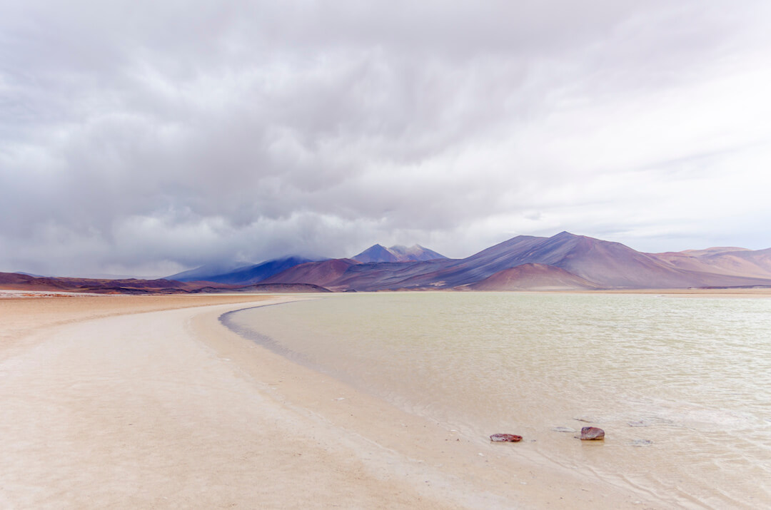 Laguna transparente y montañas bajo cielo nublado