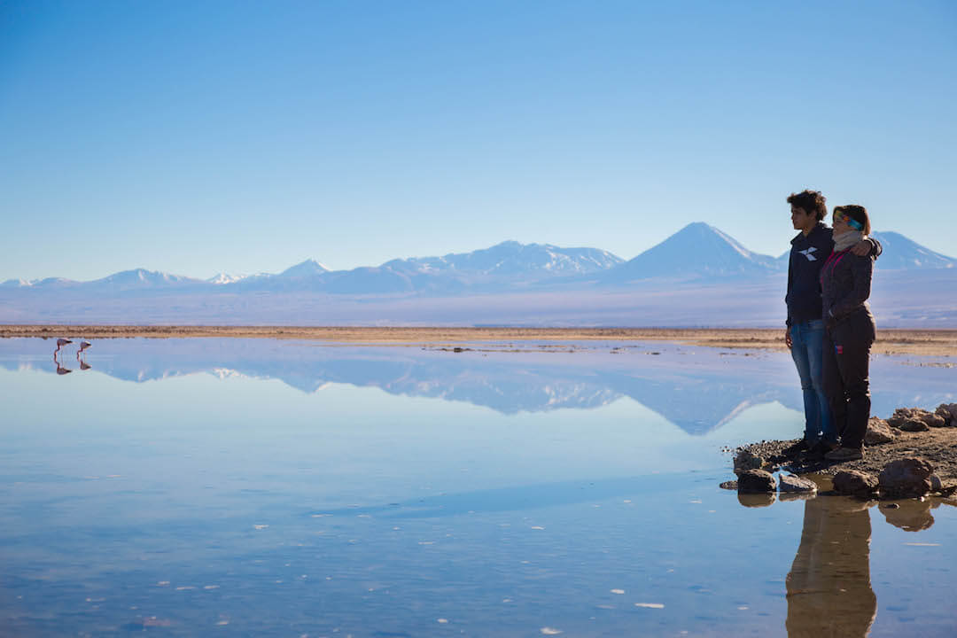Pareja observa laguna y montañas en Salar de Atacama