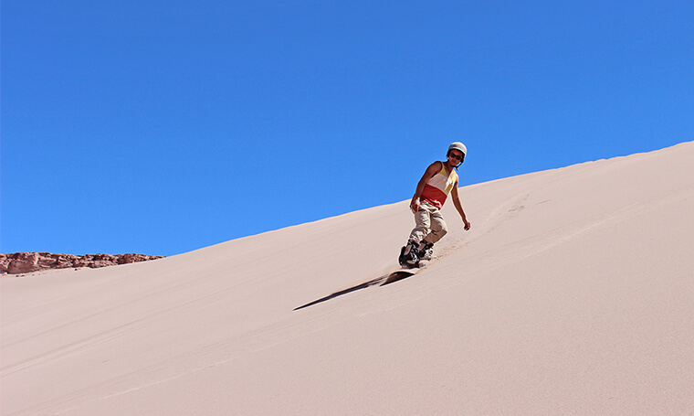sandboarder desciende por una duna en el desierto