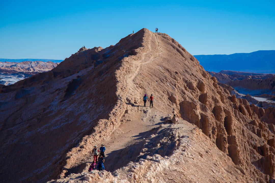 Personas caminan por un cerro de arena